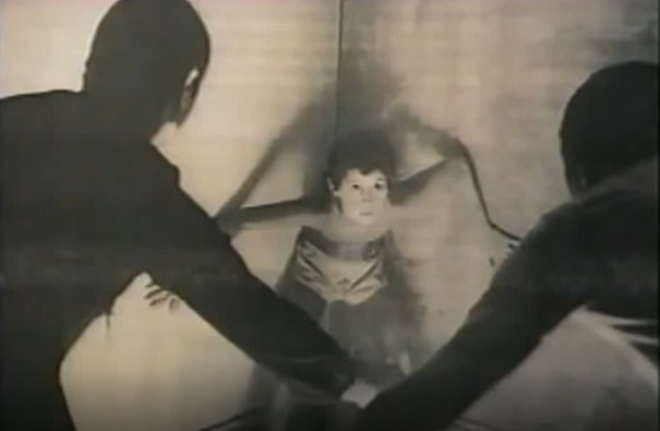 Nambla - Pokazuje przerażonego chłopca zagonionego w kąt przez dwóch dorosłych mężczyzn